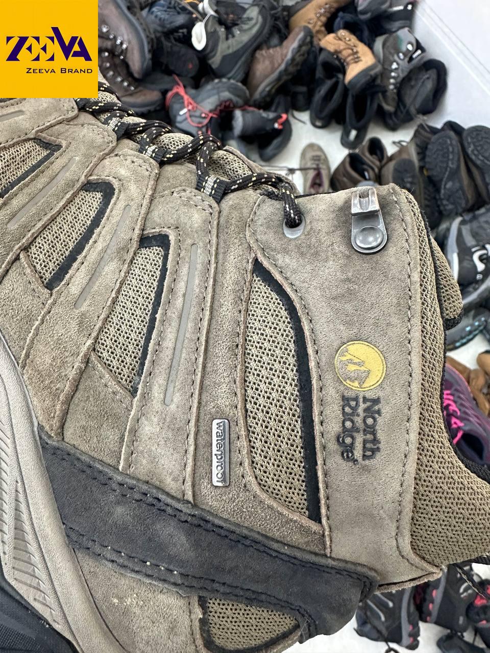 نمای نزدیک از کیفیت ساخت کتونی کوهنوردی برند Merrell” • دلیل: از برند استفاده شده و به کیفیت محصول اشاره دارد.
